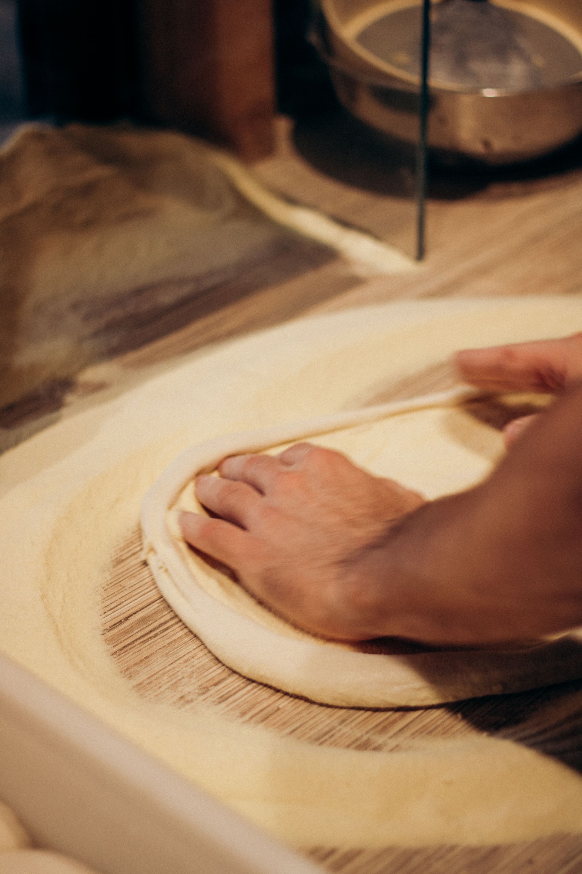 Hände ziehen frischen Pizzateig aus
